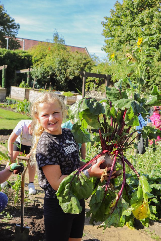 Children holding plants in a garden