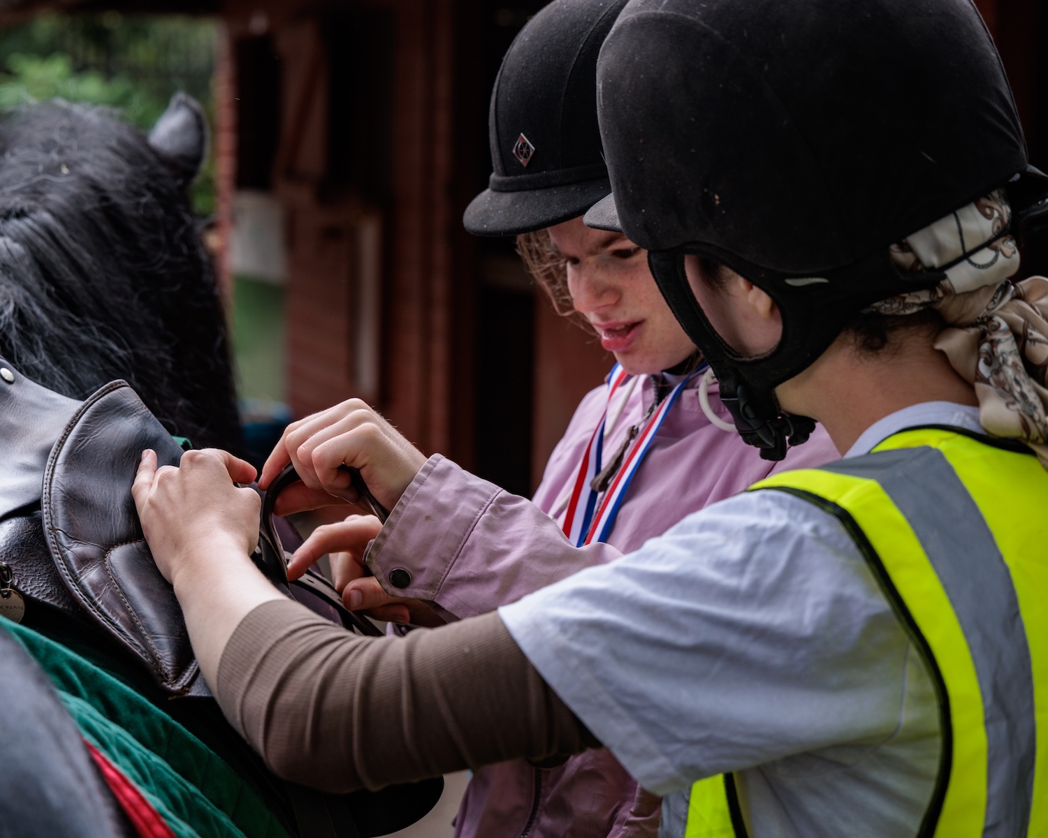 horse rider and instructor looking at a saddle strap