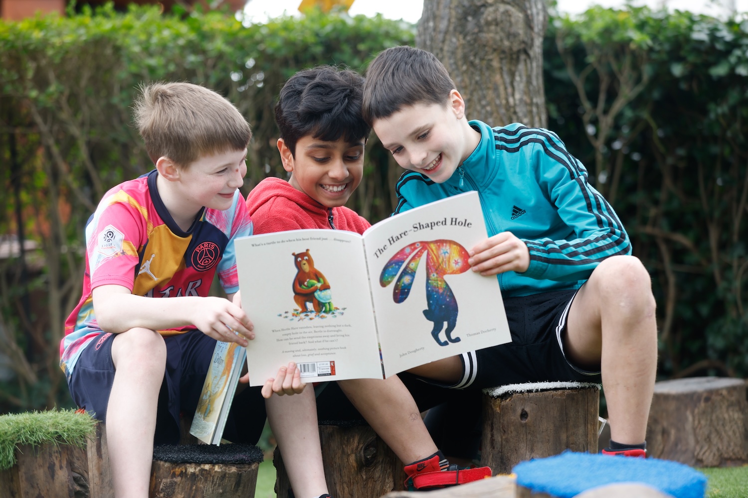 3 children laughing whilst reading book together