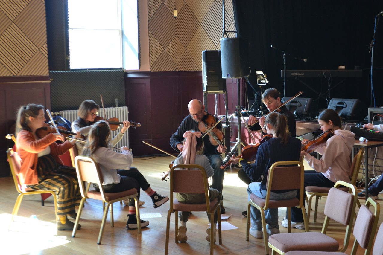a group of musicians playing violins in a circle